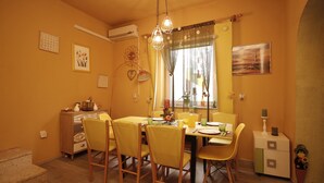A dining area with yellow chairs, a table set for four, and a window with curtains. - Holiday house Vesna for relaxed vacation (Medulin)