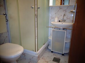 A bathroom with a toilet, a shower enclosure, a sink, and a mirror. - Nice Studio apartments Eduard (Medulin)