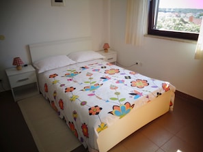 A bedroom with a bed, nightstands, and a window with a view. - Nice Studio apartments Eduard (Medulin)