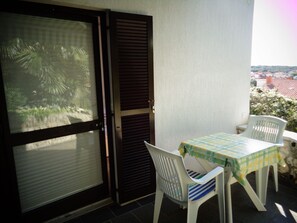 A balcony with a table and chairs, a sliding door, and a view of a cityscape. - Nice Studio apartments Eduard (Medulin)