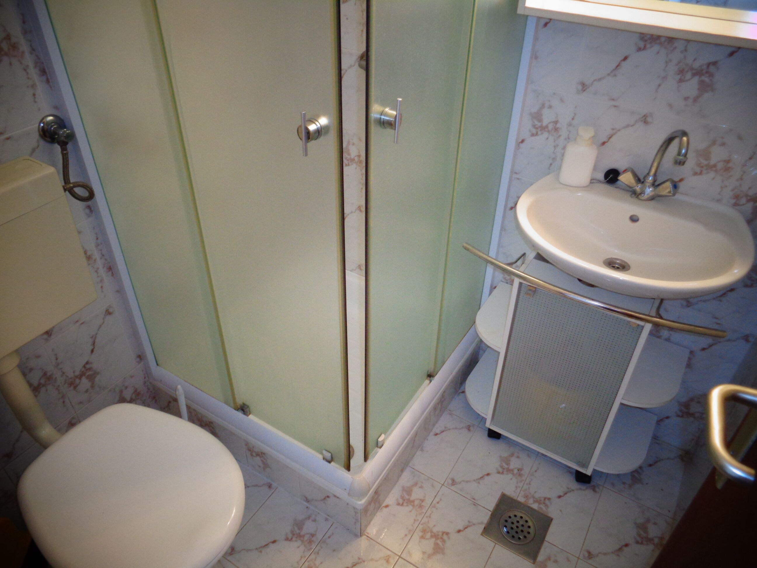Et badeværelse med toilet, brusebad og vask.