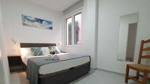 Una camera da letto con un letto, un comodino, una sedia, una finestra e un quadro appeso al muro.