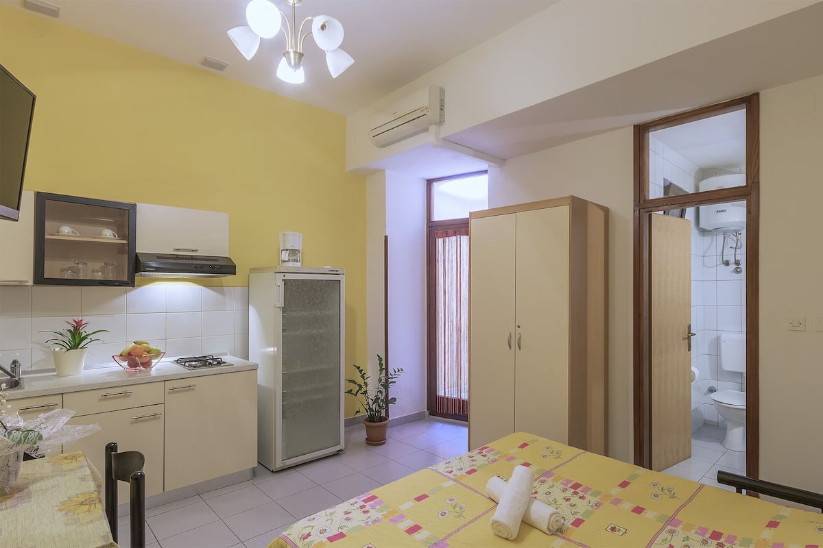 Une chambre d’hôtel compacte comprenant un coin cuisine, un espace repas et une salle de bain.