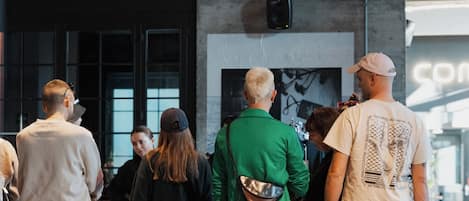 A group of people standing in a modern indoor space with exposed brick walls and a high ceiling.
