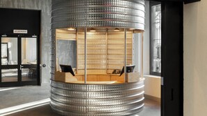 A modern interior with a neon sign reading "COMBO" above a circular seating area with a glass partition. - Combo Torino - Hostel (Turin)