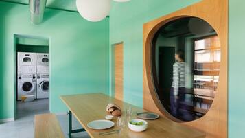 Una cocina moderna con una mesa de madera dispuesta para comer, un ventanal y la vista de una persona al fondo.