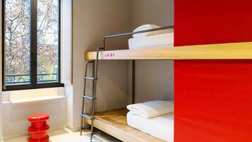 A bunk bed with a ladder, a window with a view of trees, and a red stool.