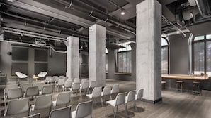 A modern conference room with rows of chairs, a bar area, and large windows. - Combo Torino - Hostel (Turin)