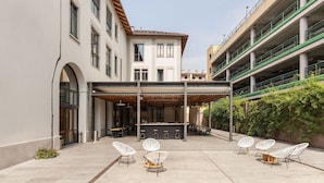 A courtyard with outdoor seating, a bar, and a covered area. - Combo Torino - Hostel (Turin)