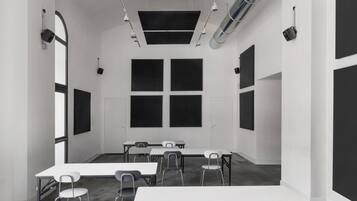 Un salón de conferencias con una larga mesa, varias sillas y múltiples pantallas negras en las paredes.