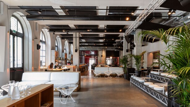 A spacious indoor area with high ceilings, large windows, and a mix of seating arrangements including a white sofa and modern chairs. - Combo Torino - Hostel (Turin)