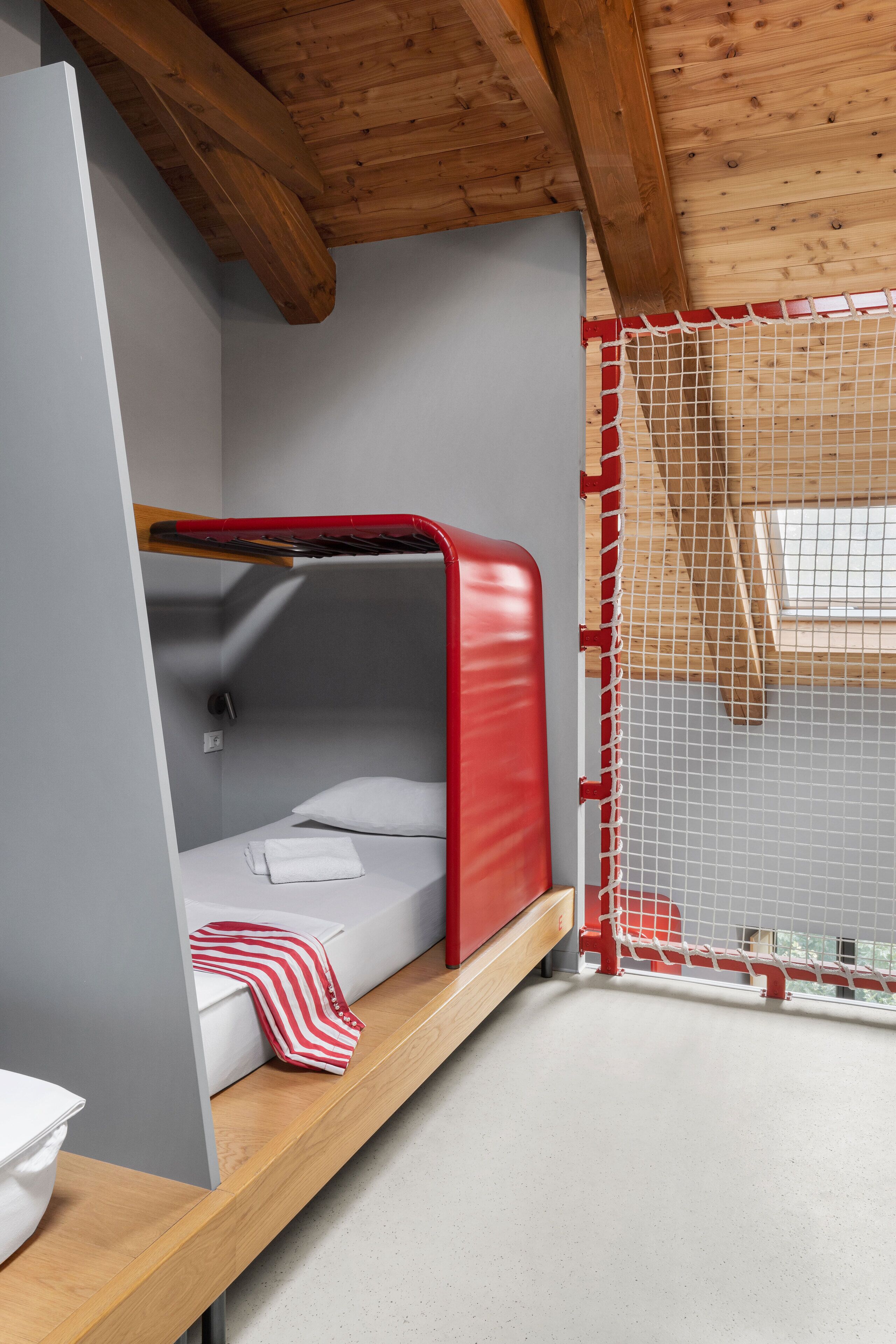 A bunk bed with a red headboard, a white pillow, and a striped towel on the lower bunk.
