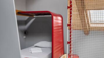 A bunk bed with a red headboard, a white pillow, and a striped towel on the lower bunk.