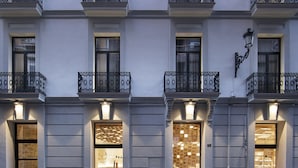 A multi-story building with balconies, large windows, and illuminated storefronts. - Hotel Serawa Alicante (Alicante)