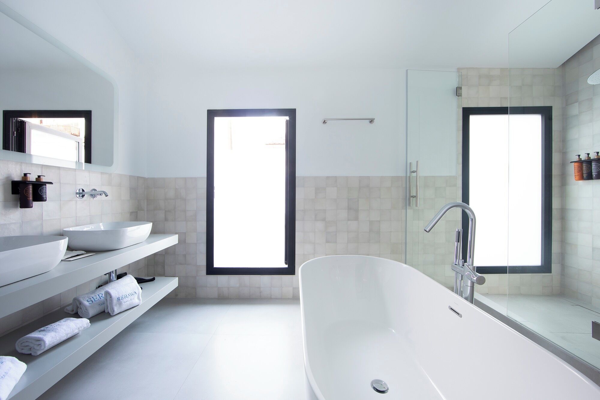 Une salle de bain moderne avec une baignoire sur pieds, deux vasques et un grand miroir.