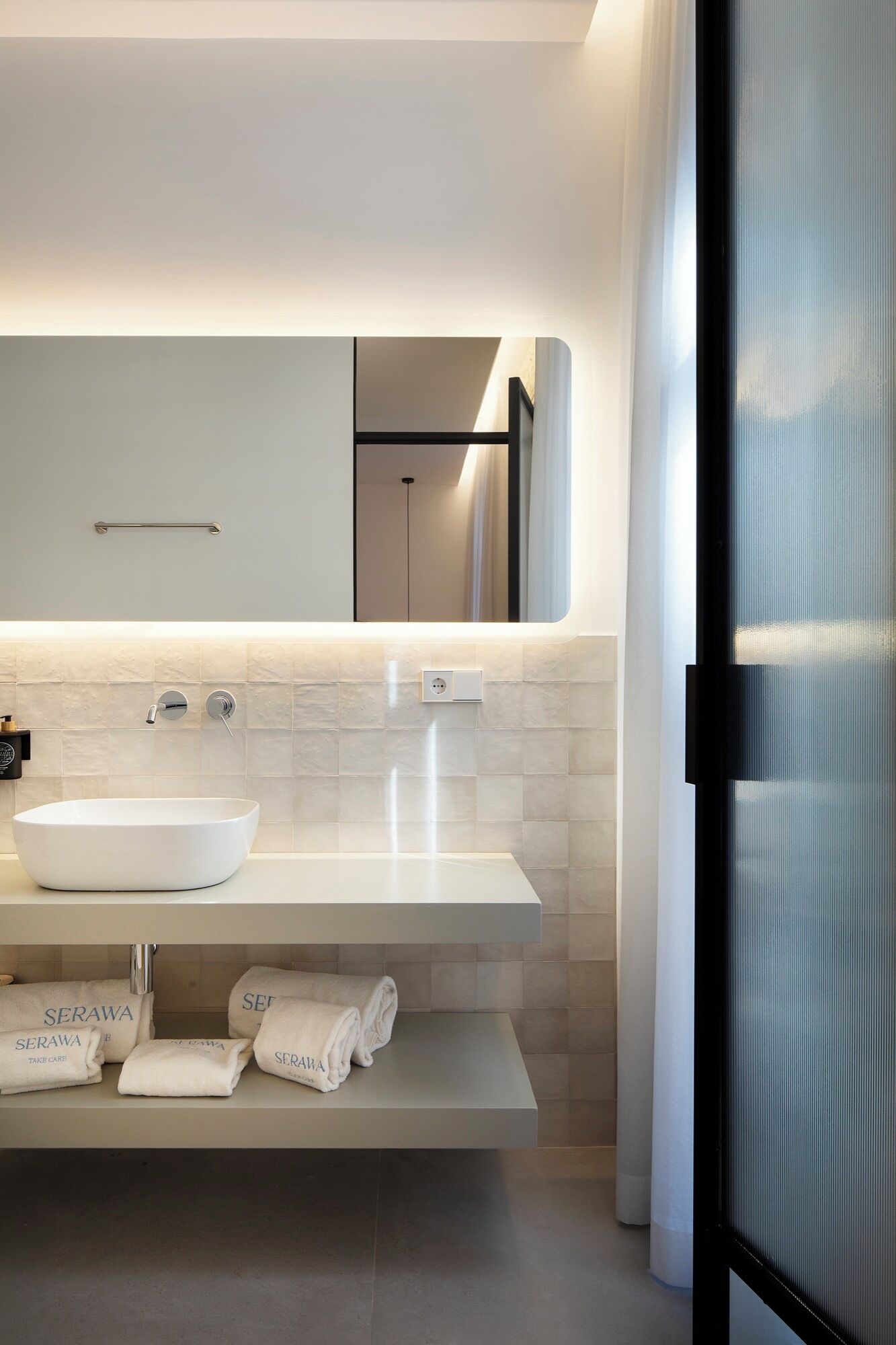 Een moderne badkamer met een wit wastafelmeubel, een spiegel en een handdoekhouder.