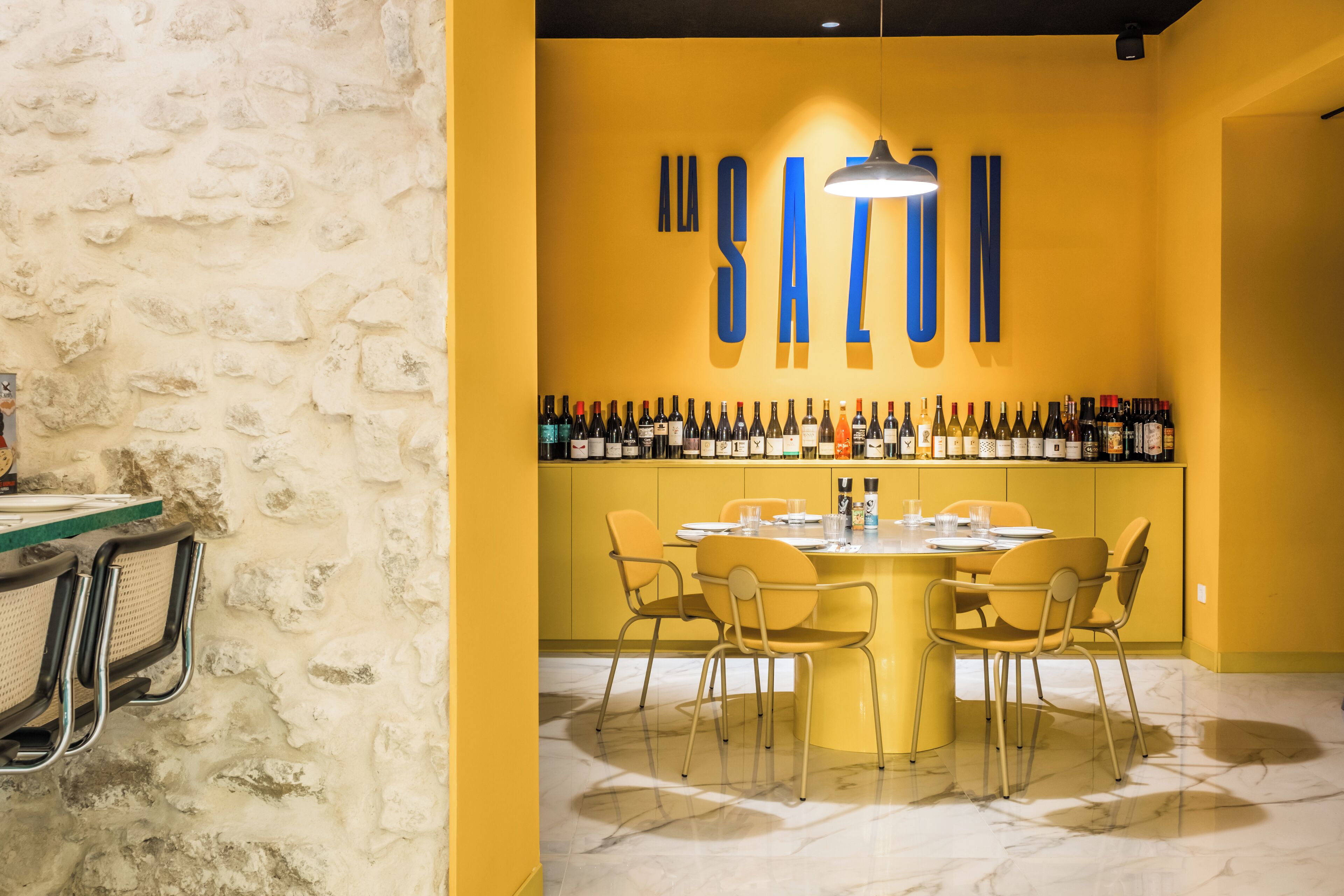 A yellow-themed bar area with a marble floor, a round table, and multiple chairs.