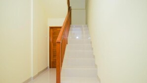 A staircase with wooden handrails and white steps leading to a wooden door at the top. - Bali Billy Village (Canggu)