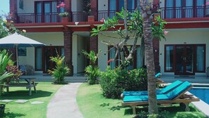 A two-story building with a red-tiled roof, a covered patio, and a swimming pool. - Bali Billy Village (Canggu)