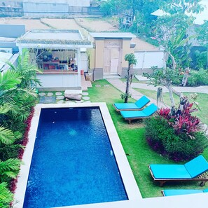 A swimming pool with lounge chairs, a bar area, and a small garden with various plants. - Bali Billy Village (Canggu)