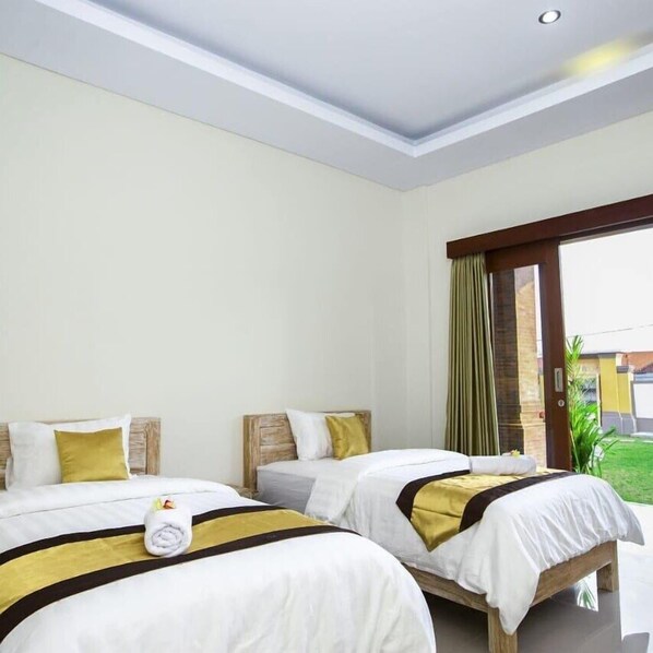 A hotel room with two beds, a large window with curtains, and a view of the outdoors. - Bali Billy Village (Canggu)
