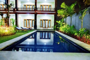 A swimming pool with lounge chairs and a building with balconies. - Bali Billy Village (Canggu)