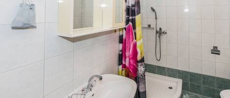 A bathroom with a white sink, a shower with a colorful curtain, and a mirror above the sink.