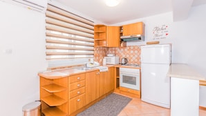 A compact kitchen with wooden cabinets, a built-in oven, and a white refrigerator. - Affordable Apartment Bruno in Pula (Pula)