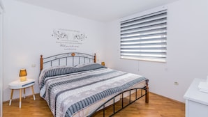 A neatly arranged bedroom with a bed, bedside table, and a wall decoration. - Affordable Apartment Bruno in Pula (Pula)