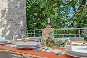 A table set outdoors with plates, glasses, and a bottle, surrounded by greenery.