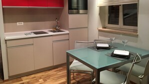 Une cuisine compacte équipée d’un évier, d’appareils électroménagers modernes et d’un coin repas avec une table et des chaises.