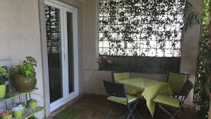 A patio with a table and chairs, surrounded by potted plants and a sliding glass door. - Comfortable Nena Apartment with Nice View (Medulin)