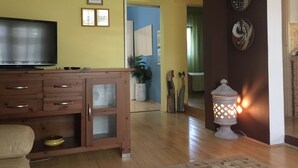 A living room with a wooden cabinet, a flat-screen TV, and a decorative wall lamp. - Comfortable Nena Apartment with Nice View (Medulin)