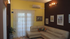 A living room with a beige sectional sofa, a potted plant, a wooden coffee table, and a large window with sheer curtains. - Comfortable Nena Apartment with Nice View (Medulin)