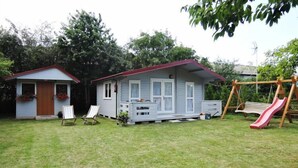 A house with a red roof, a porch with two chairs, and a swing set with a slide.