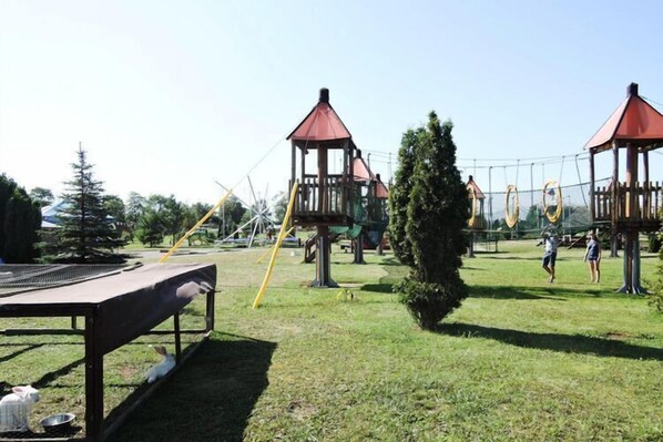 A playground with swings, a climbing structure, and a fenced area.
