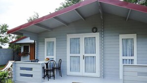 A single-story house with a porch, a dining table and chairs, and a small garden area.