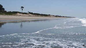 Ein Strand mit sandigem Ufer und sanften Wellen.