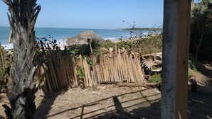 Blick auf einen Strand mit einer reetgedeckten Hütte und einem Holzzaun.