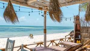 A beachside lounge with wooden furniture and a view of the ocean. - Pili Pili House (Jambiani)