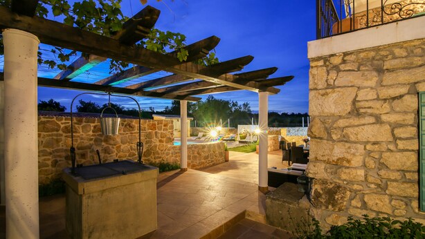 An outdoor patio area with stone walls, a pergola, and a pool. - Stunning Villa Bozini Dvori (Sveti Filip i Jakov)