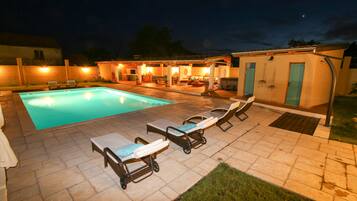 A swimming pool area with lounge chairs and a patio.