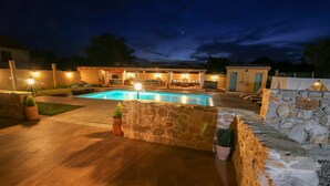 A nighttime view of a pool area with stone walls and outdoor seating. - Stunning Villa Bozini Dvori (Sveti Filip i Jakov)