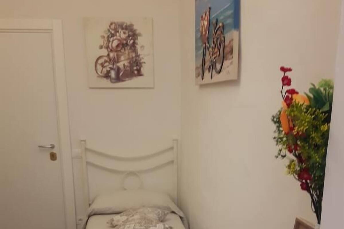 Une chambre à coucher bien rangée, avec un lit, des oreillers, une petite table sur laquelle sont posés des articles de toilette et une étagère murale décorative.