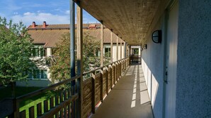 A corridor with a wooden railing, a concrete floor, and a view of houses and trees. - Volontärgatan - Visby Lägenhetshotell (Visby)