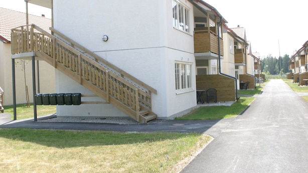 A residential building with a staircase leading to a balcony, a small outdoor seating area, and a paved pathway. - Volontärgatan - Visby Lägenhetshotell (Visby)