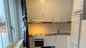 A compact kitchen with white cabinets, a Bosch oven, and a white refrigerator. - Volontärgatan - Visby Lägenhetshotell (Visby)