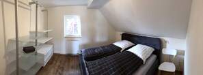 Un dormitorio con una cama, una ventana, una estantería de vidrio y una silla.