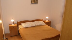 A single bed with a wooden headboard and footboard, flanked by two bedside tables with lamps. - Lorena Apartments (Pula)