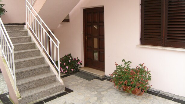 A staircase with white railings leading to an upper floor, a wooden door, and a window with wooden shutters. - Lorena Apartments (Pula)
